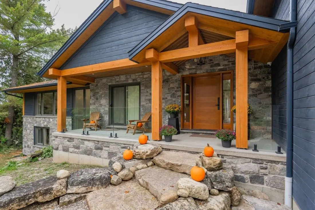 Rustic home entrance with custom wood posts and beams designed by Homestead Woodworks, combining natural stone and wood elements